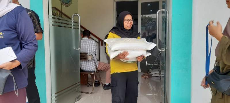 Salah seorang warga usai menerima bahan pangan beras di Kelurahan Bakti Jaya, Kecamatan Setu, Kota Tangsel.