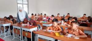 Siswi belajar dengan gedung sekolah yang baru